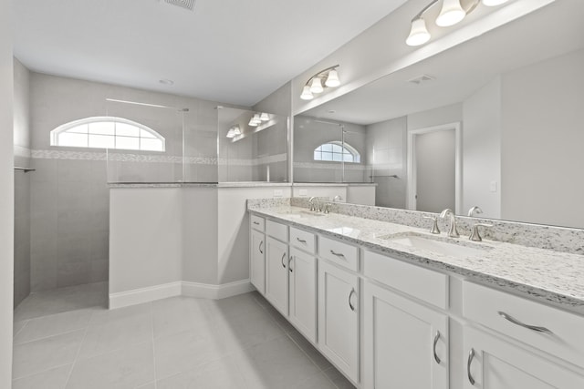 bathroom featuring tile patterned floors, a wealth of natural light, tiled shower, and vanity