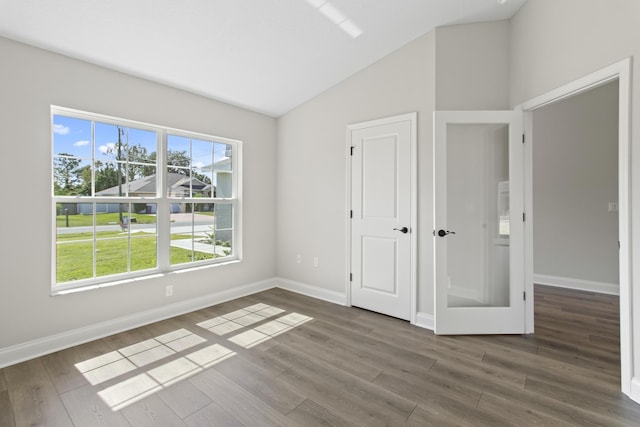 unfurnished bedroom featuring multiple windows, dark hardwood / wood-style floors, and vaulted ceiling