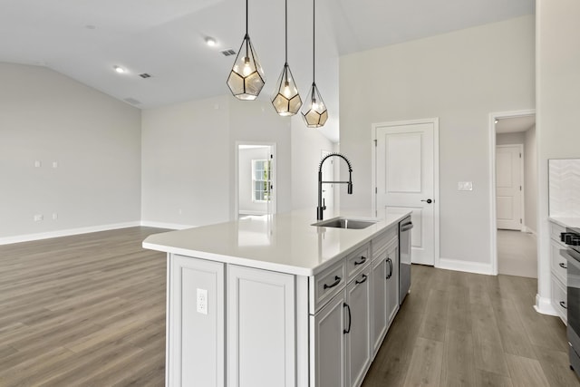 kitchen with a center island with sink, lofted ceiling, pendant lighting, stainless steel dishwasher, and sink