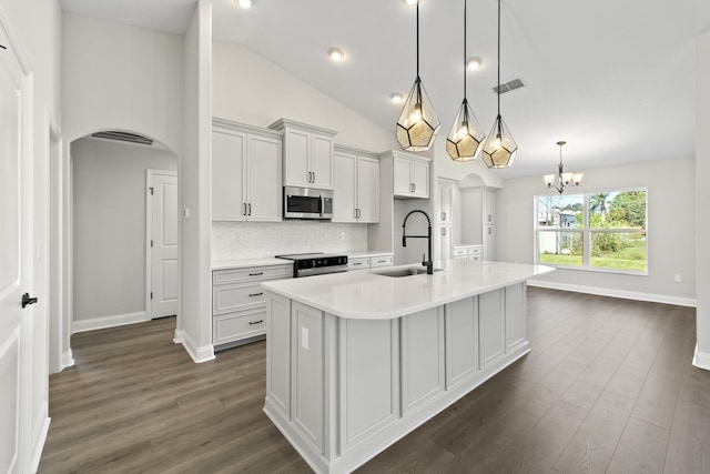 kitchen featuring decorative light fixtures, tasteful backsplash, sink, electric stove, and a center island with sink