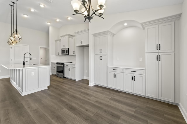 kitchen featuring vaulted ceiling, pendant lighting, white cabinetry, appliances with stainless steel finishes, and an island with sink