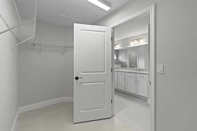 walk in closet with light tile patterned floors and sink