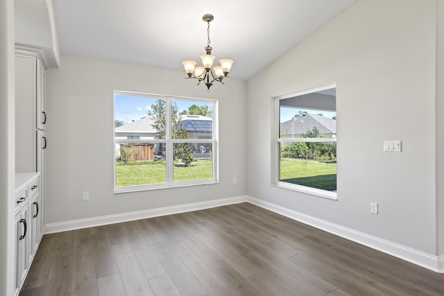 interior space featuring dark wood-type flooring, vaulted ceiling, and an inviting chandelier