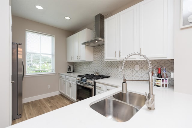 kitchen with stainless steel appliances, wall chimney range hood, backsplash, and white cabinets