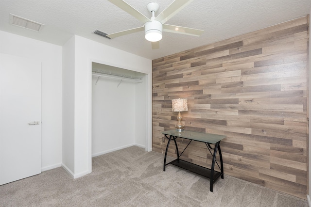 carpeted bedroom with wooden walls, visible vents, and a textured ceiling