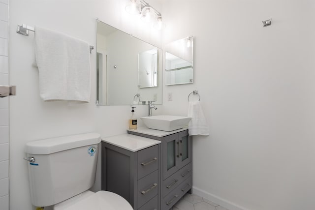 bathroom with tile patterned flooring, baseboards, vanity, and toilet