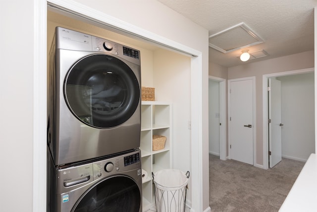 laundry area featuring laundry area, attic access, stacked washer and clothes dryer, a textured ceiling, and carpet floors