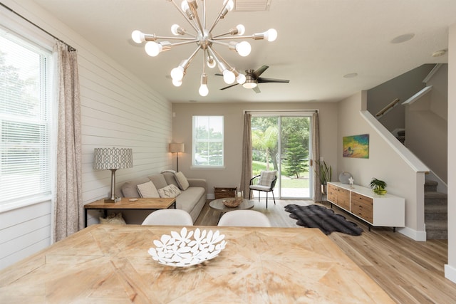 dining room featuring a chandelier, wood walls, stairway, and wood finished floors