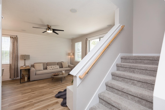 staircase featuring a ceiling fan and wood finished floors