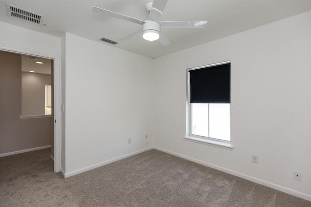 carpeted empty room featuring baseboards, visible vents, and a ceiling fan