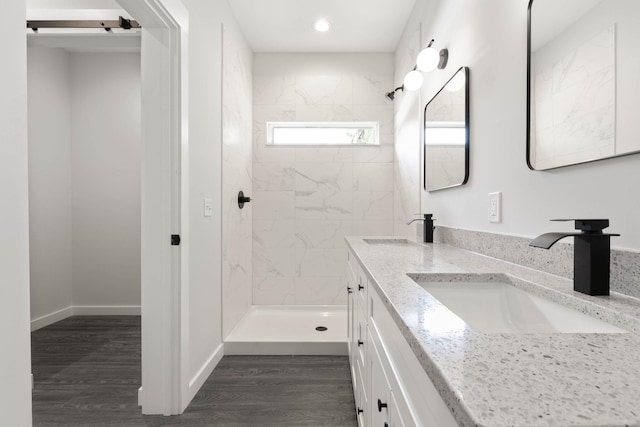 bathroom featuring hardwood / wood-style flooring, vanity, and a tile shower