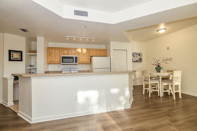 kitchen featuring dark hardwood / wood-style flooring, white appliances, and a center island