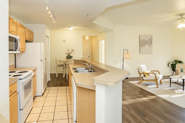 kitchen featuring white appliances, sink, light brown cabinets, a center island with sink, and light hardwood / wood-style floors