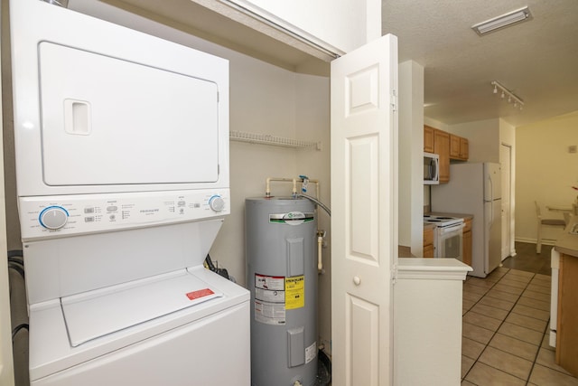 laundry area with a textured ceiling, light tile patterned flooring, electric water heater, and stacked washer and dryer