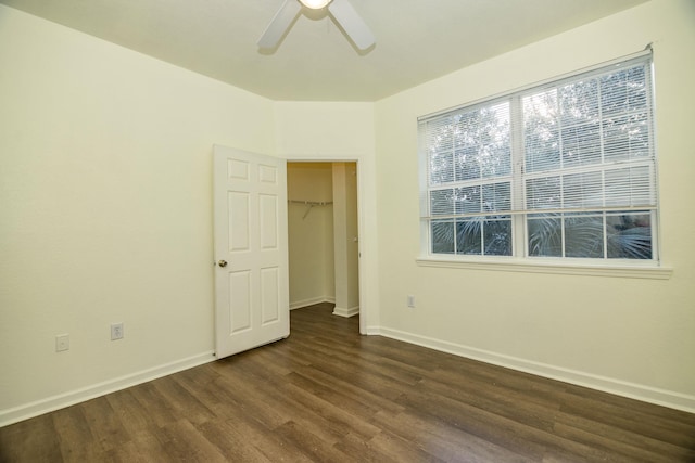 unfurnished bedroom featuring dark hardwood / wood-style flooring, a closet, a spacious closet, and ceiling fan