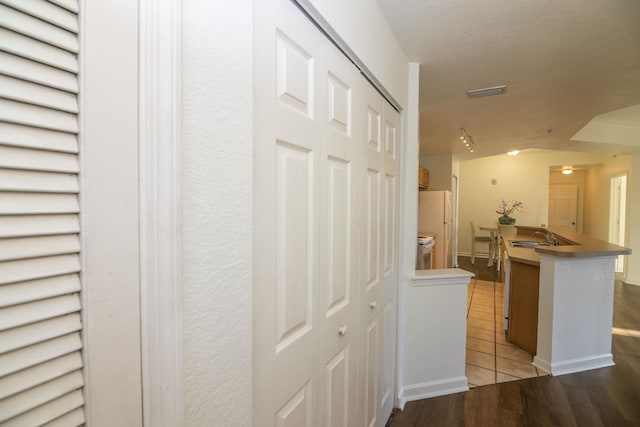 hall featuring sink, light hardwood / wood-style floors, and a textured ceiling