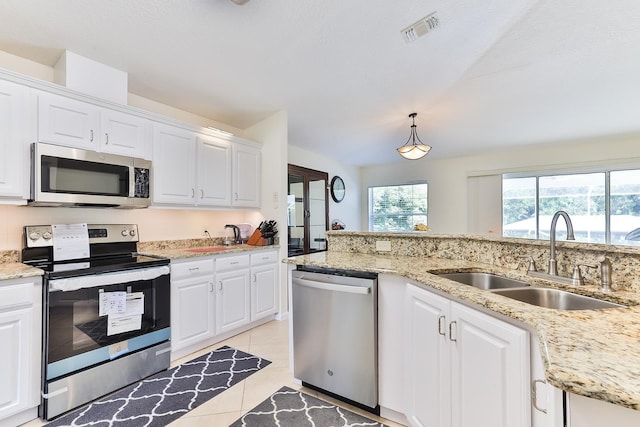 kitchen with hanging light fixtures, sink, appliances with stainless steel finishes, light tile patterned flooring, and white cabinetry