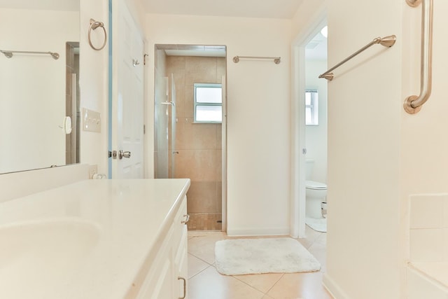 bathroom with tile patterned floors, vanity, toilet, and tiled shower