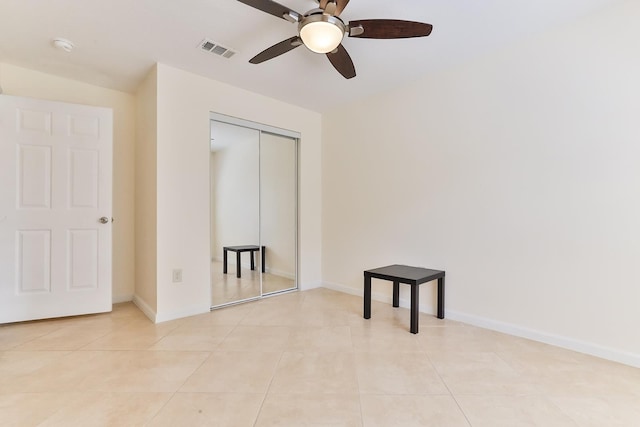 unfurnished bedroom with ceiling fan, a closet, and light tile patterned floors