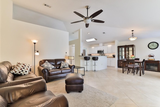 tiled living room with ceiling fan and vaulted ceiling