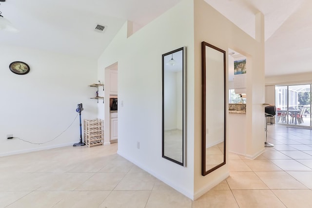 corridor with light tile patterned floors and lofted ceiling