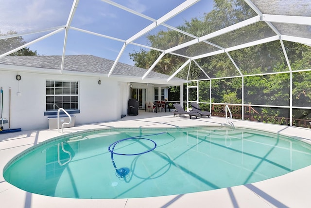 view of swimming pool with glass enclosure, ceiling fan, and a patio