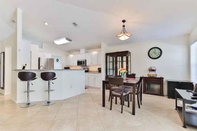 kitchen featuring kitchen peninsula, appliances with stainless steel finishes, light stone counters, white cabinetry, and lofted ceiling