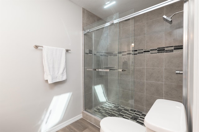 full bath featuring toilet, a shower stall, and baseboards