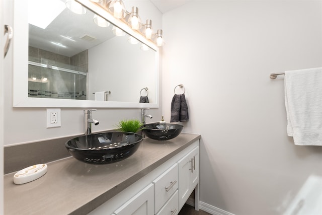 bathroom with a shower stall and double vanity