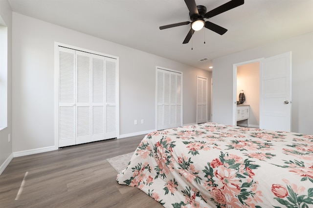 bedroom with two closets, wood finished floors, baseboards, and ceiling fan