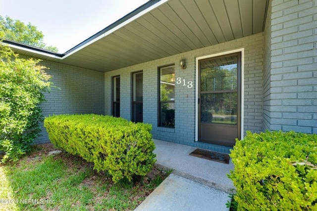 doorway to property featuring brick siding and covered porch
