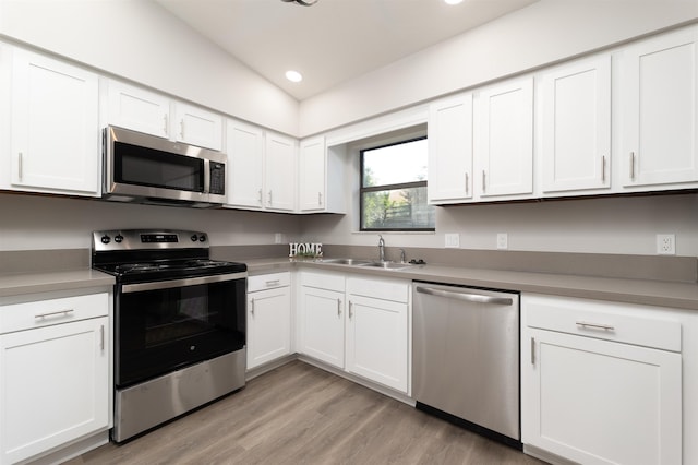 kitchen featuring stainless steel appliances, a sink, white cabinetry, light wood-style floors, and recessed lighting