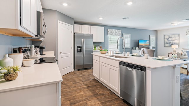 kitchen featuring appliances with stainless steel finishes, a sink, dark wood-style flooring, open floor plan, and light countertops