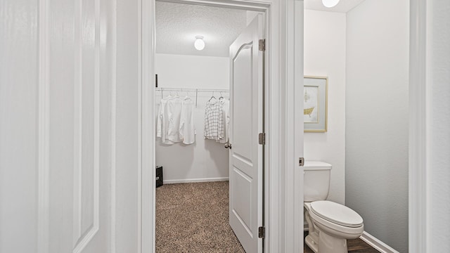 bathroom with a textured ceiling, toilet, and baseboards