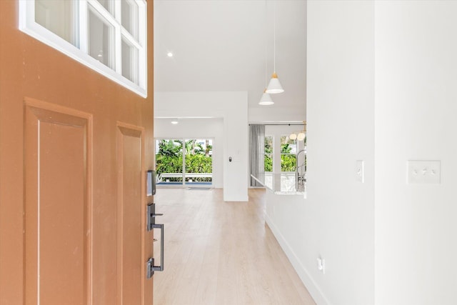 entrance foyer with light wood-style flooring, a high ceiling, and baseboards