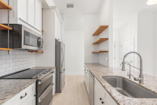 kitchen featuring a sink, open shelves, white cabinetry, light wood-style floors, and appliances with stainless steel finishes