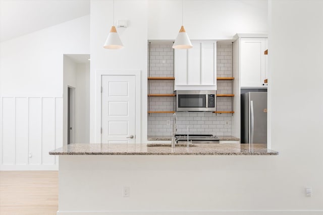 kitchen featuring light stone counters, open shelves, a sink, stainless steel appliances, and white cabinetry