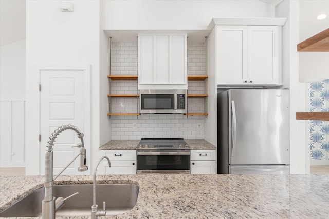 kitchen featuring open shelves, a sink, stainless steel appliances, white cabinets, and tasteful backsplash