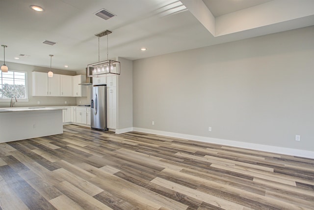 kitchen featuring white cabinetry, stainless steel fridge with ice dispenser, decorative light fixtures, and light wood-type flooring