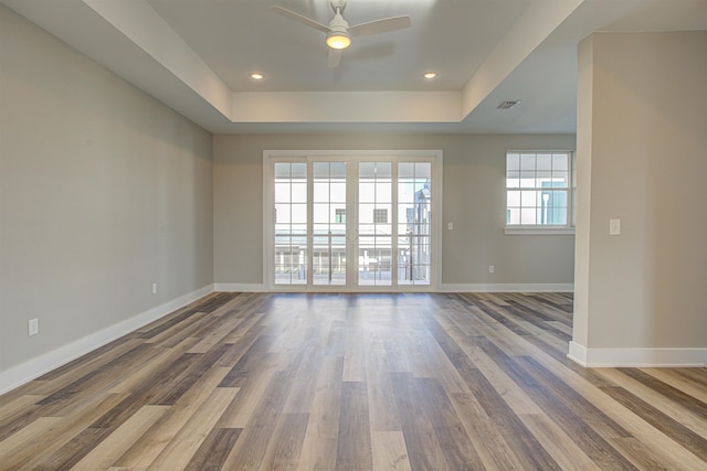 unfurnished room with ceiling fan, wood-type flooring, and a tray ceiling