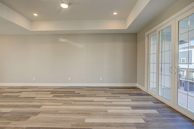 empty room featuring light hardwood / wood-style floors, french doors, and a raised ceiling