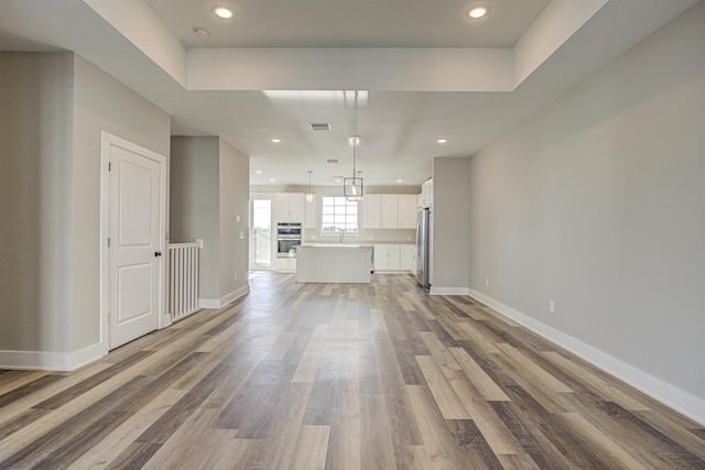 unfurnished living room featuring wood-type flooring and sink