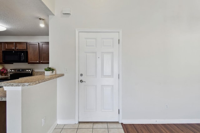 kitchen with dark brown cabinetry, stainless steel electric range oven, a peninsula, light countertops, and black microwave