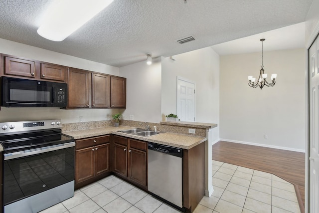 kitchen featuring a peninsula, stainless steel appliances, light countertops, a sink, and light tile patterned flooring