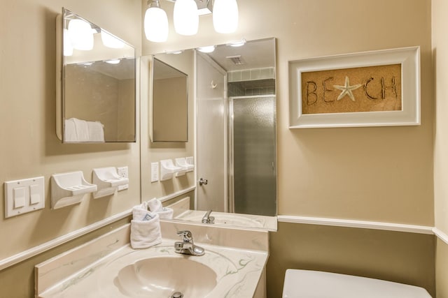 bathroom featuring a shower with shower door, vanity, and toilet