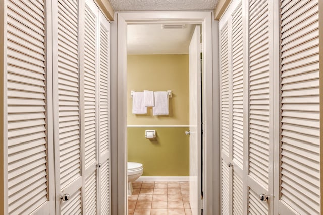 bathroom with visible vents, toilet, tile patterned flooring, a textured ceiling, and a closet