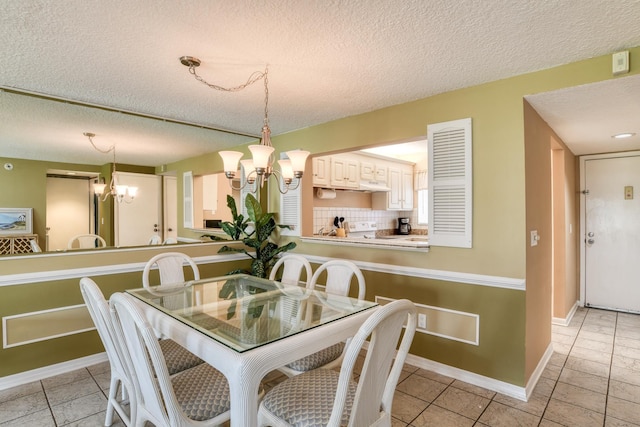 dining area with a textured ceiling, baseboards, and an inviting chandelier