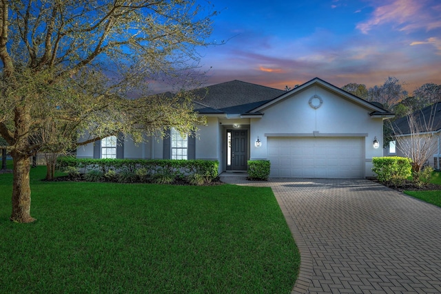 ranch-style home with a shingled roof, a front lawn, stucco siding, decorative driveway, and a garage