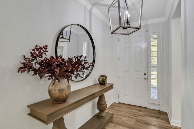 foyer featuring baseboards, a notable chandelier, wood finished floors, and crown molding