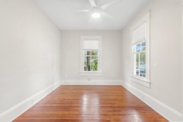 empty room with hardwood / wood-style floors, a wealth of natural light, and ceiling fan